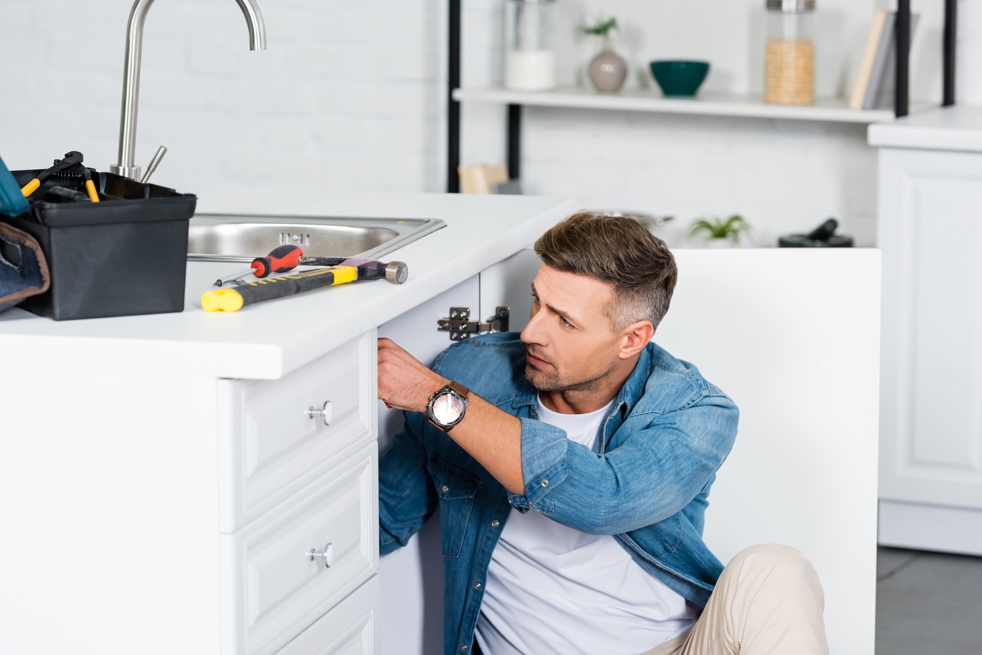 Handsome man repairing kitchen sink