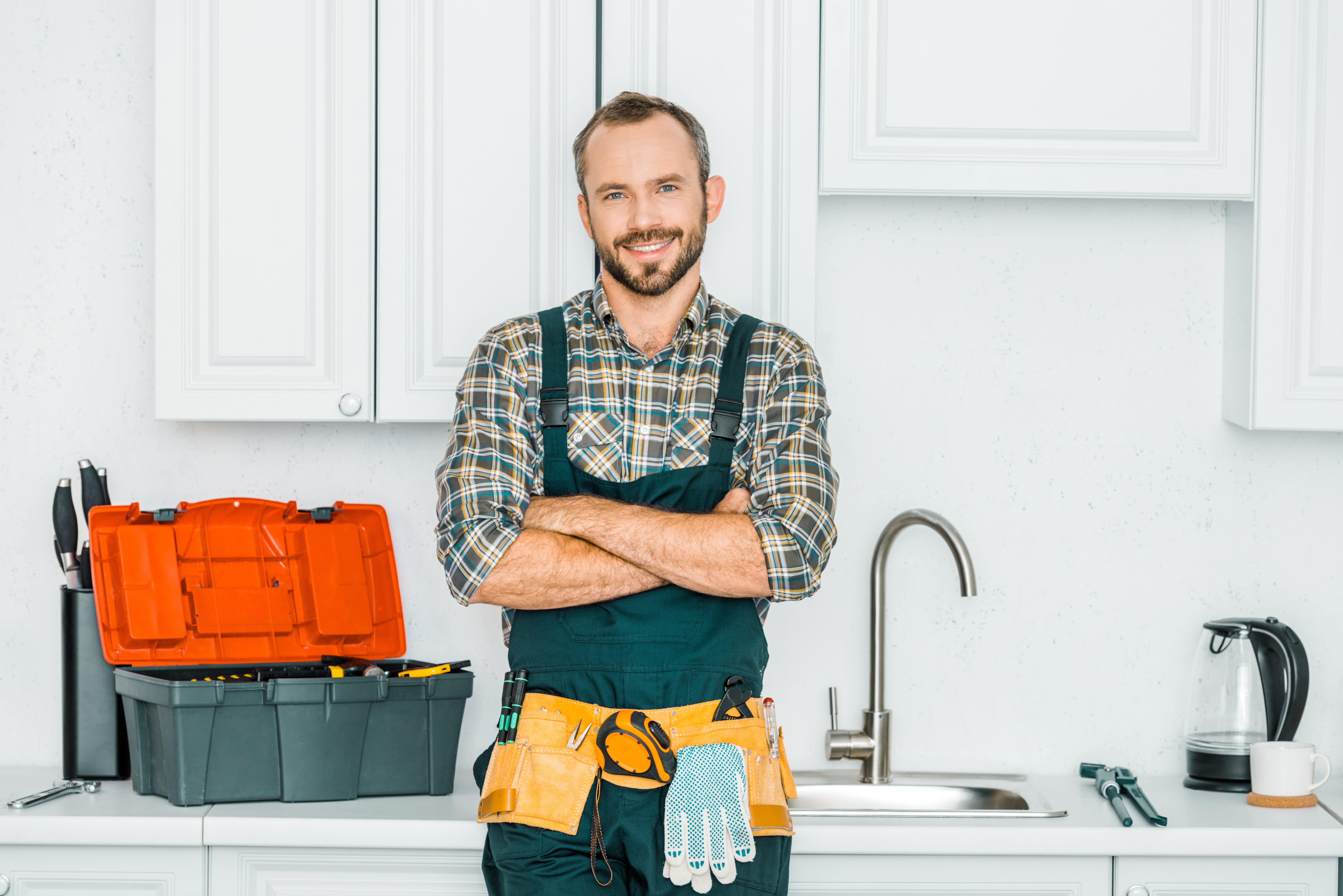 Smiling handsome plumber standing with crossed arms