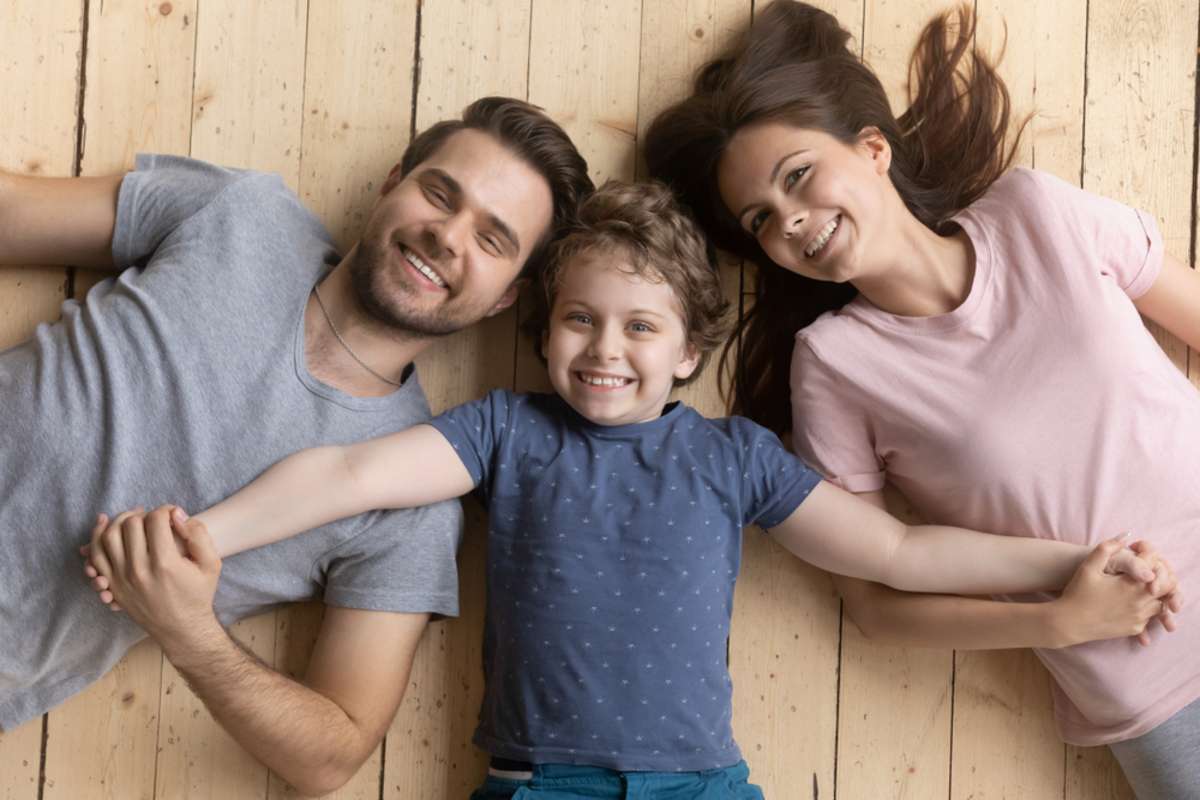 Above top view happy adopted little kid boy holding hands of smiling young family couple