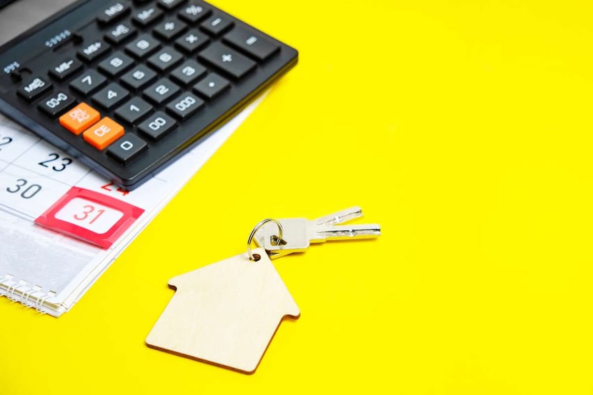 House keys with a calculator and calendar on yellow background, residential lease agreement concept. 