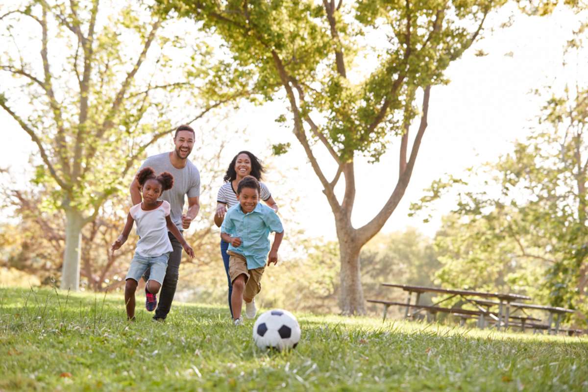 Family Playing Soccer In Park Together