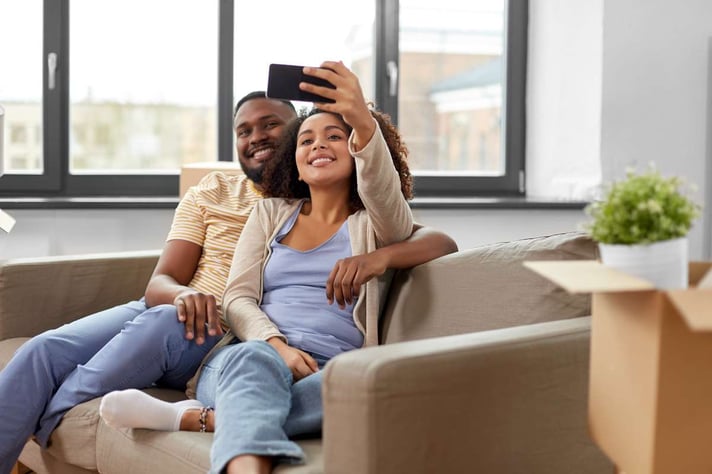 Happy couple moving to new home and taking selfie