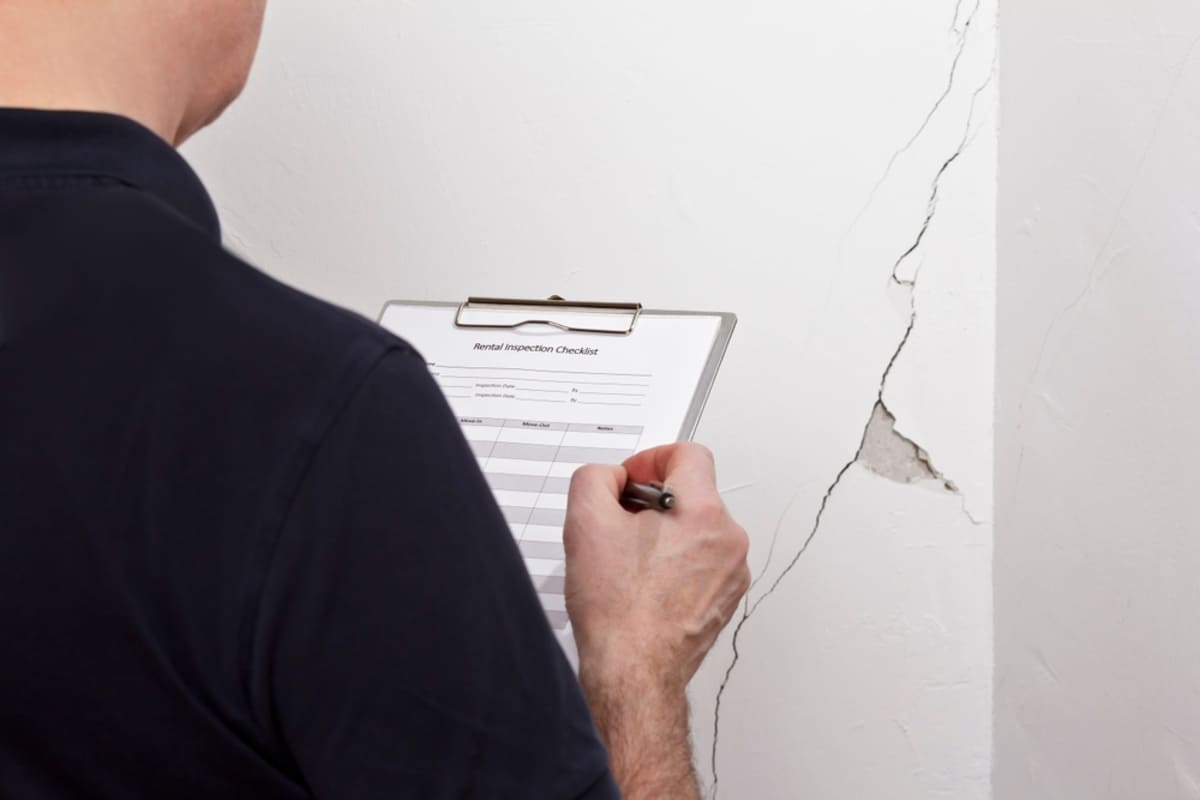 Man with a clipboard inspects a crack in the wall, Philadelphia property management inspection concept
