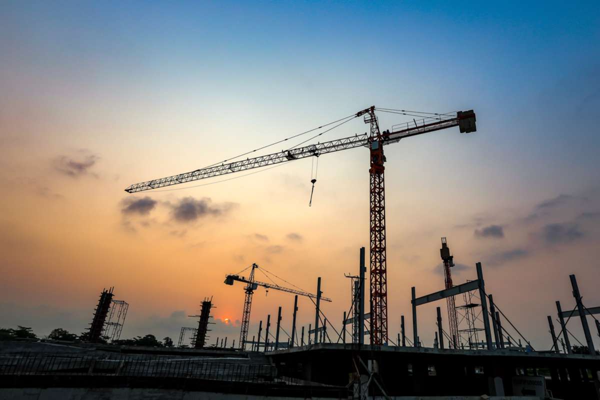 New construction site with crane and mechanical equipments on sunset background