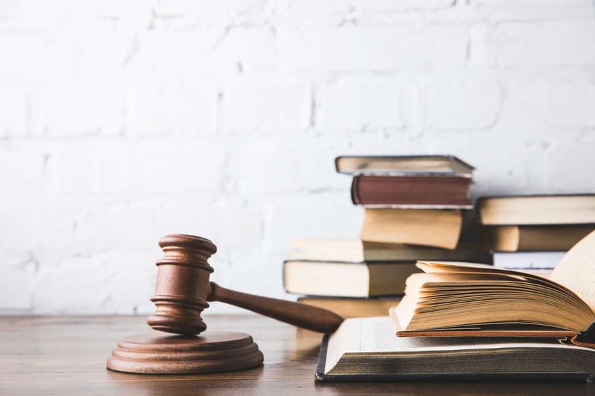 Opened juridical books with gavel on wooden table, law concept