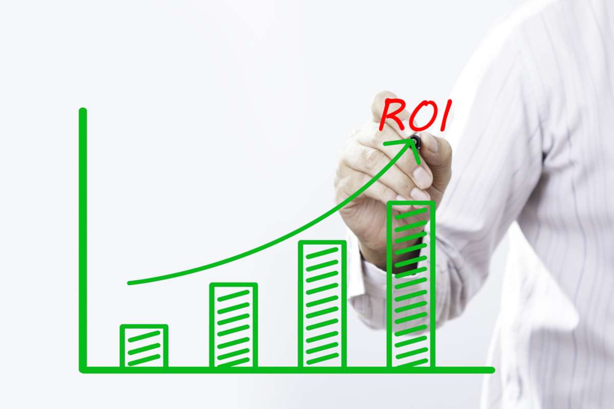ROI text with hand on virtual graph green line and bar showing increasing rental property ROI concept. 