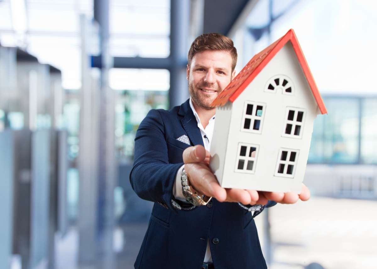 Young businessman with toy house