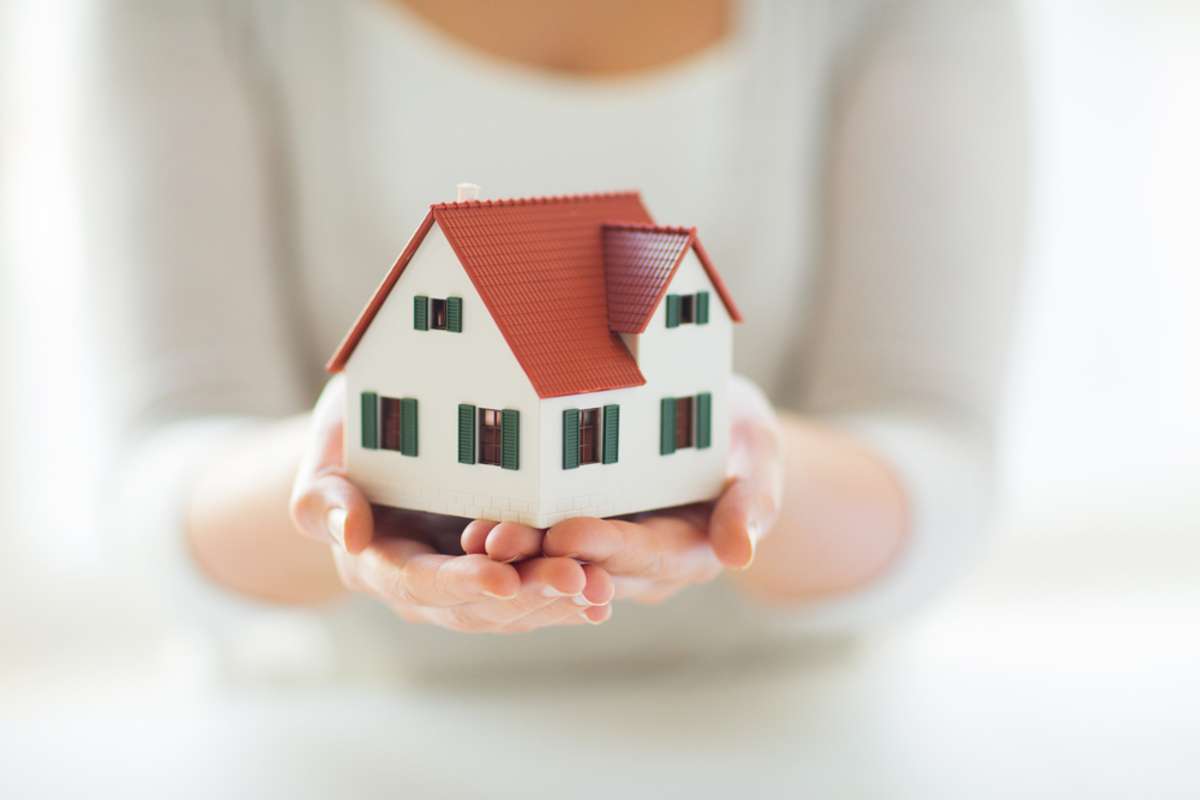 close up of hands holding house or home model