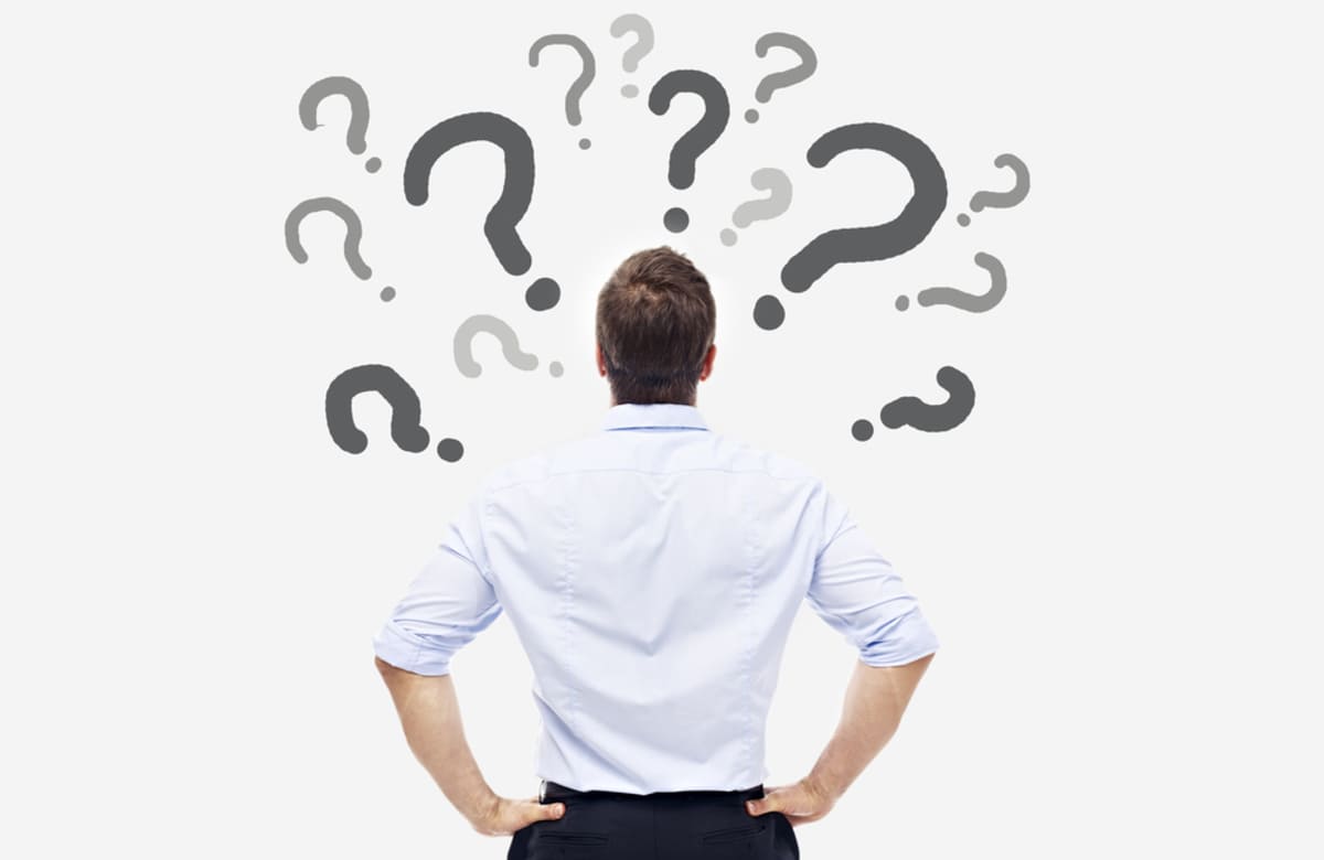 rear view of a caucasian business person looking at the question marks on white board