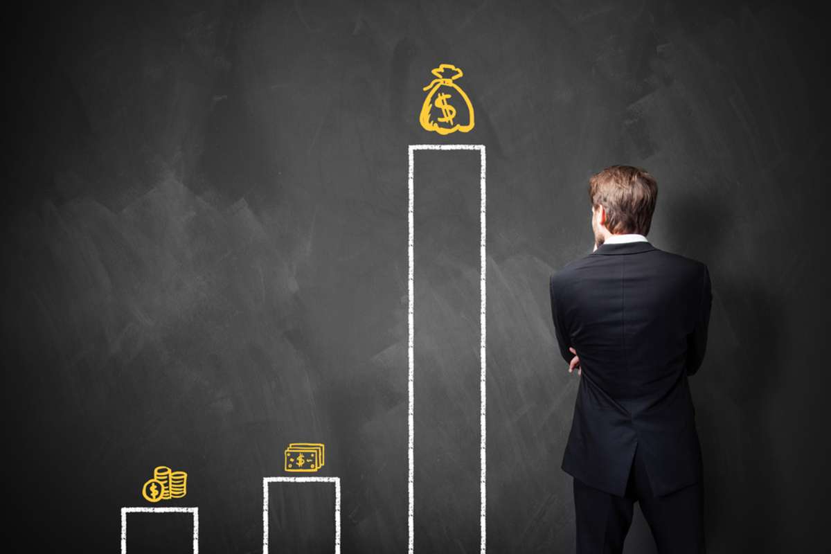 businessman standing in front of a blackboard with a chart about different types of wages