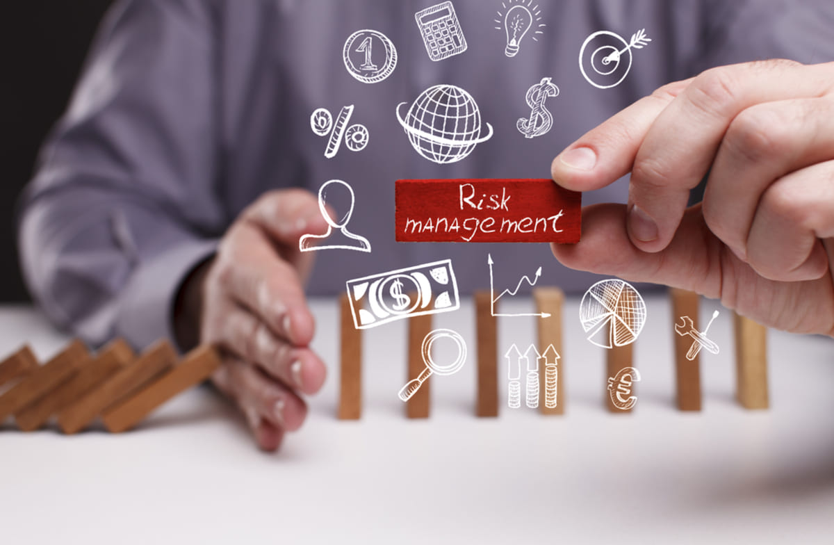 Businessman’s hand stops domino effect representing risk management