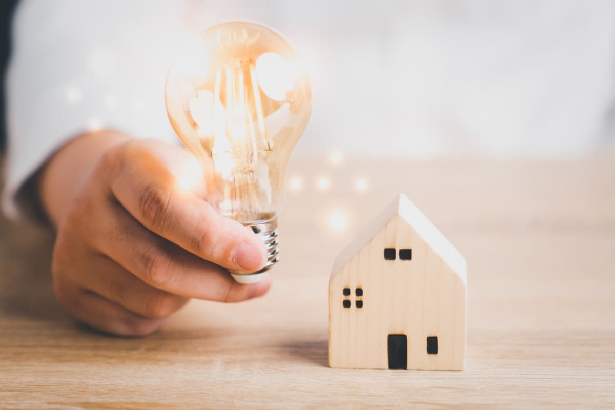 Lightbulb by house model representing innovation on real estate business models