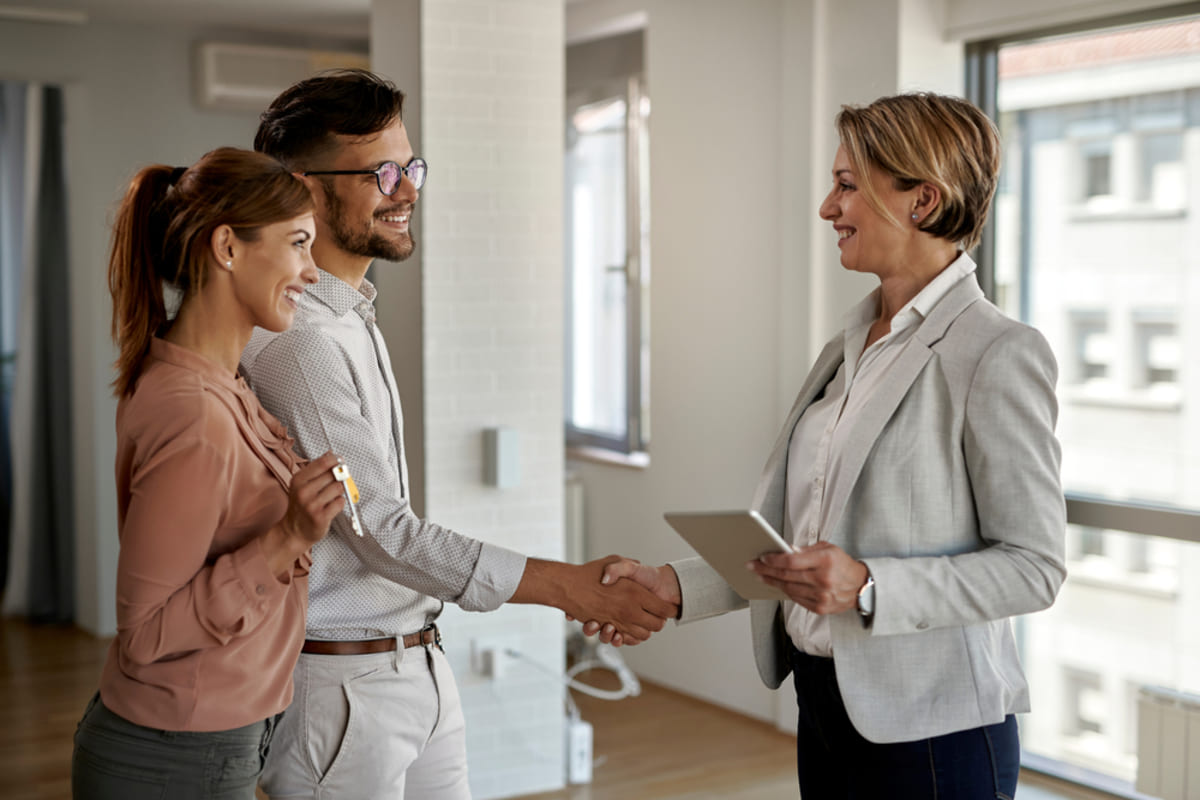 Real estate agent and couple shaking hands after agreement