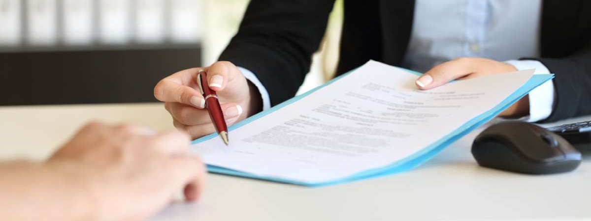 Close up of an executive hands holding a pen and indicating where to sign a contract at office