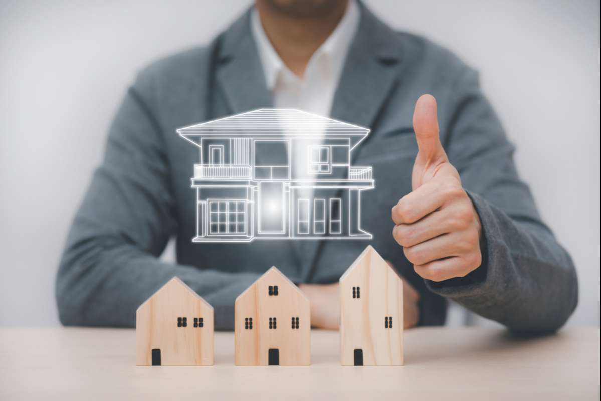 Businessman showing thumbs up mini and wood house model